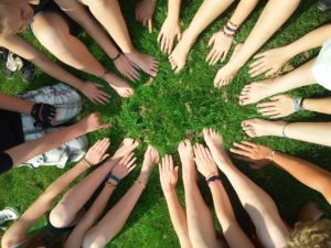 Team mates putting their feet and hands into a circle.