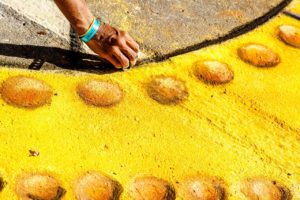 Woman drawing with yellow chalk on the street.